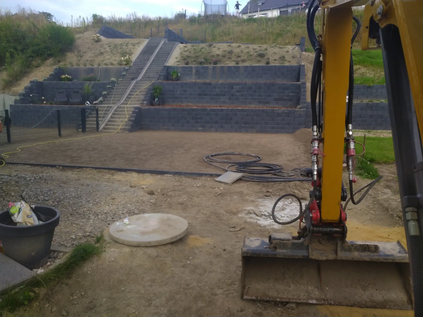 Tiefbaustelle von AT Bau mit ausgehobenem Gelände, Stützmauern und Baggerarm